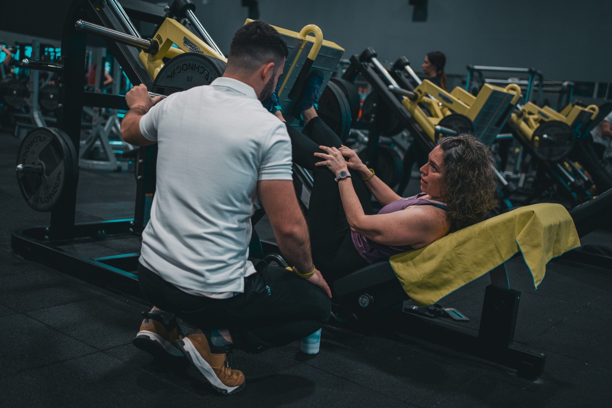 trainer working with woman on leg press machine